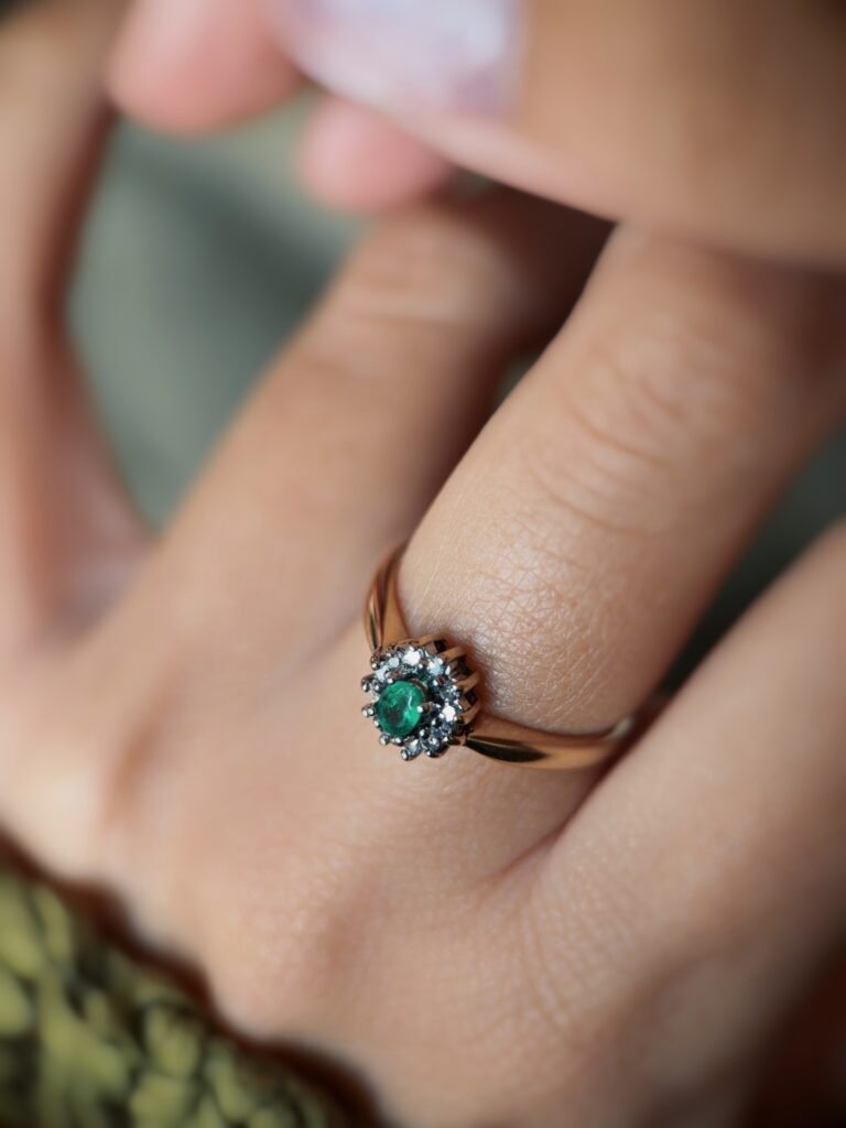 Vintage gold diana ring with oval emerald and diamonds worn on a hand