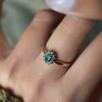 Vintage gold diana ring with oval emerald and diamonds worn on a hand