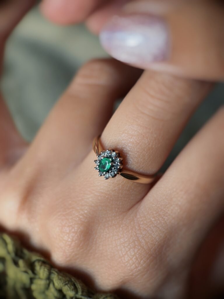 Vintage gold diana ring with oval emerald and diamonds worn on a hand