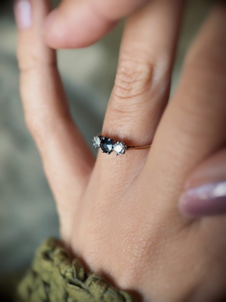 Antique 18 carat gold sapphire and old european cut diamond threestone ring worn on a hand