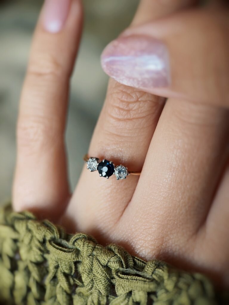Antique 18 carat gold sapphire and old european cut diamond threestone ring worn on a hand